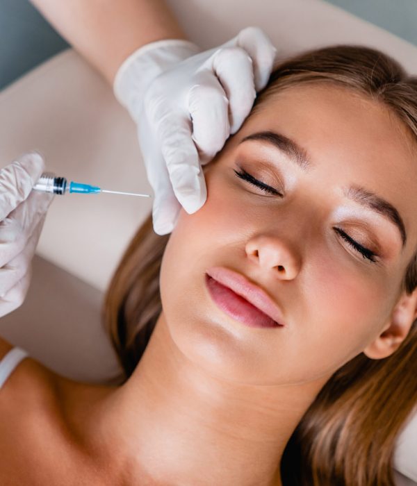 Young woman gets beauty facial injections in salon