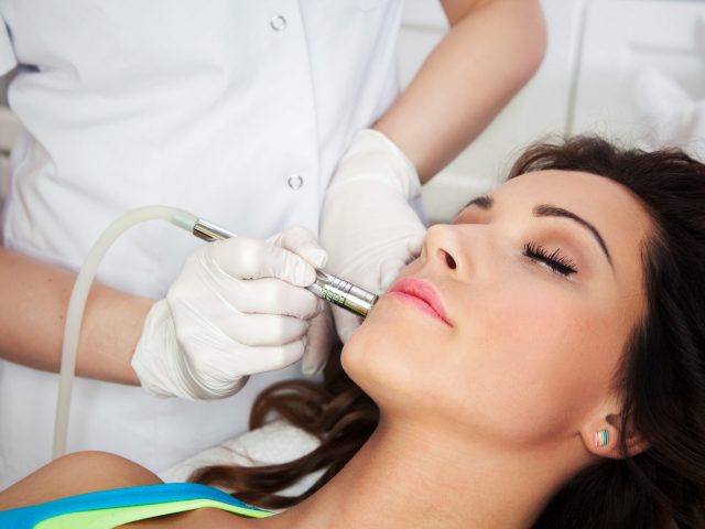 Woman getting laser face treatment in medical spa center